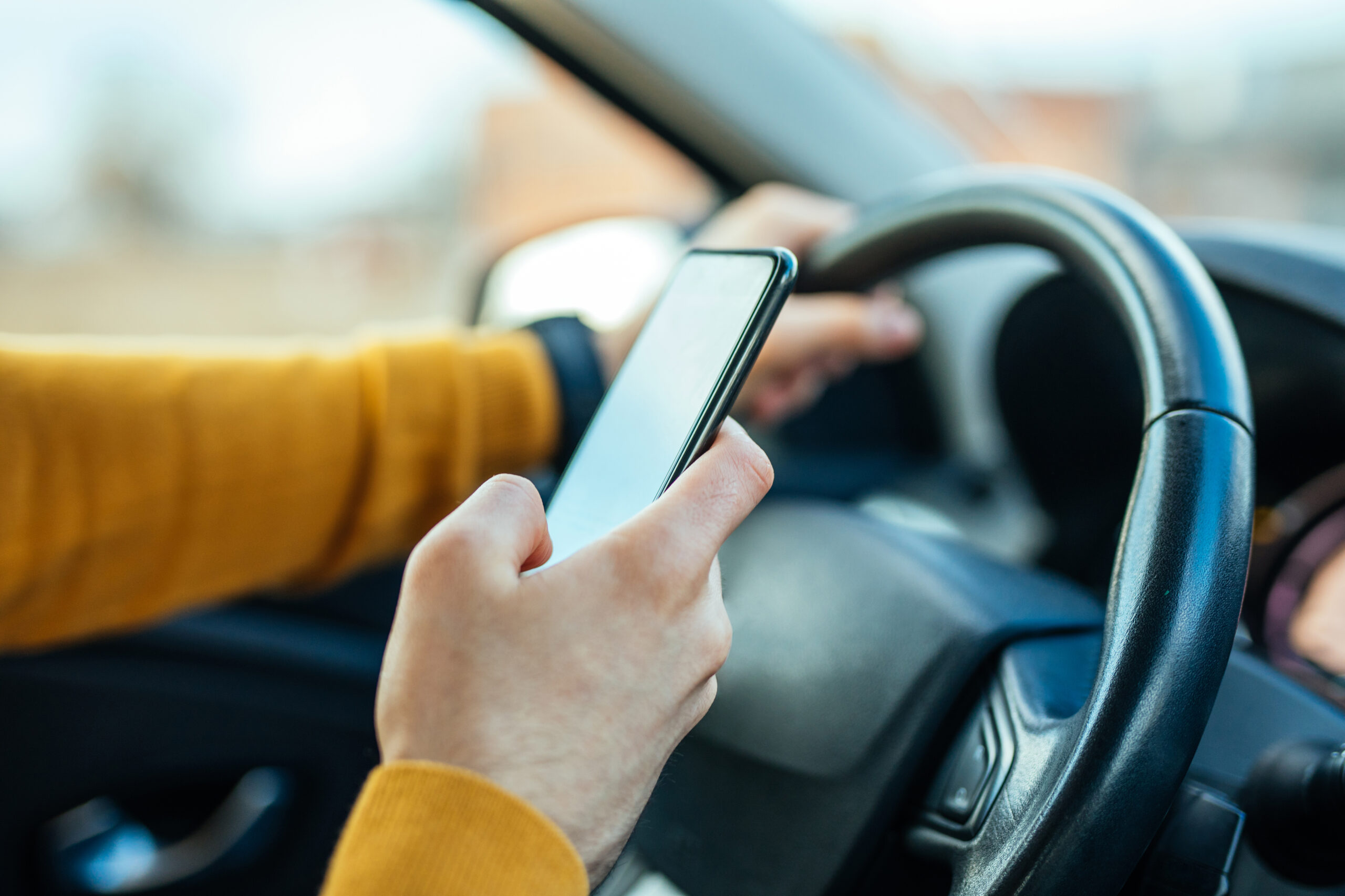 closeup of driver texting at steering wheel while driving a car